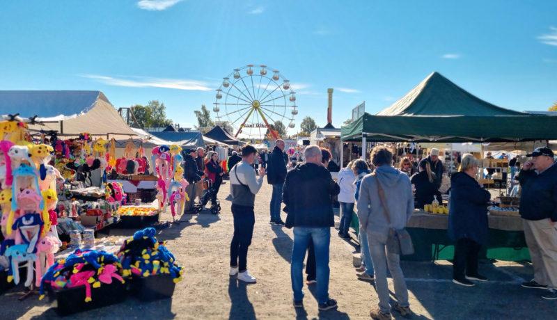 Folk på höstmarknad i Ekenäs. Pariserhjul i bakgrunden.