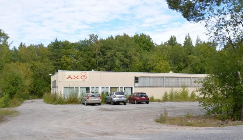 en låg industrihall med tre bilar utanför