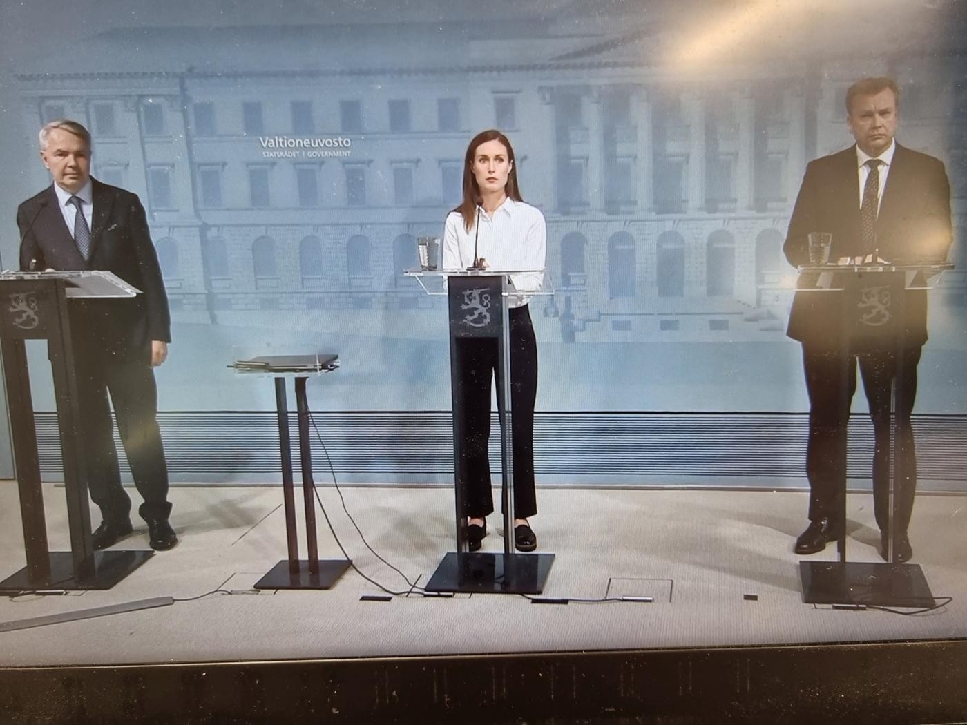 två män och en kvinna håller presskonferens