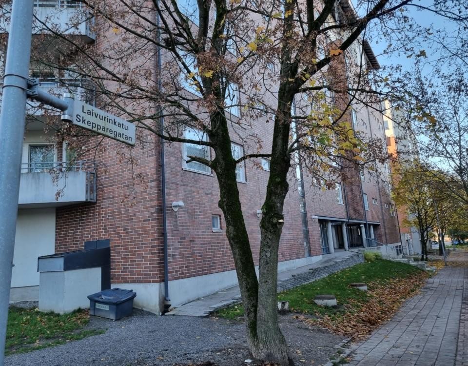 Vy av höghusområde, vägskylt med texten "Laivurinkatu, Skepparegatan"