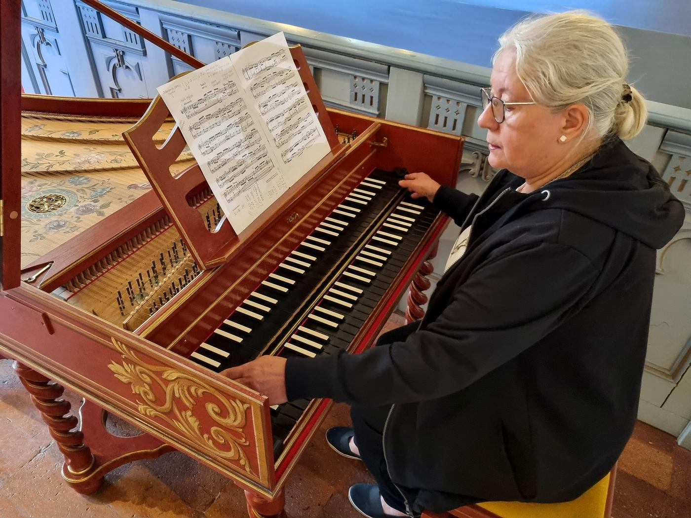 En kvinna spelar på ett flygelliknande instrument.