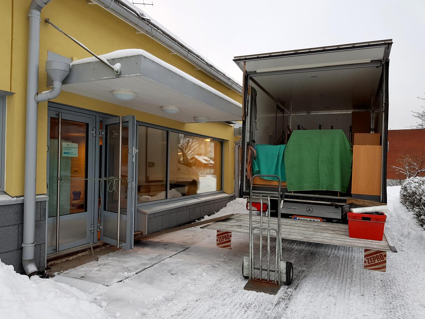 flyttbil utanför gul kontorsbyggnad