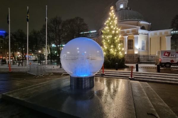 En rund glob framför en julgran och en kyrka