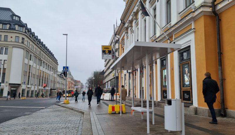 En busshållplats vid torget utanför en byggnad.