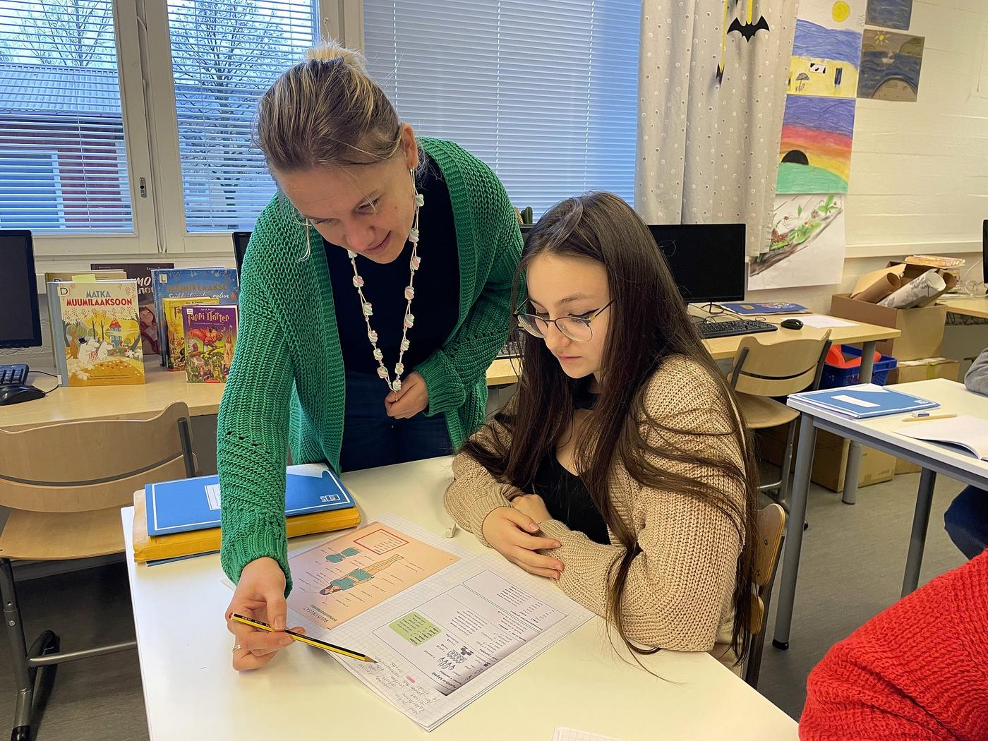elev och handledare fokuserade på en skoluppgift i häftet.