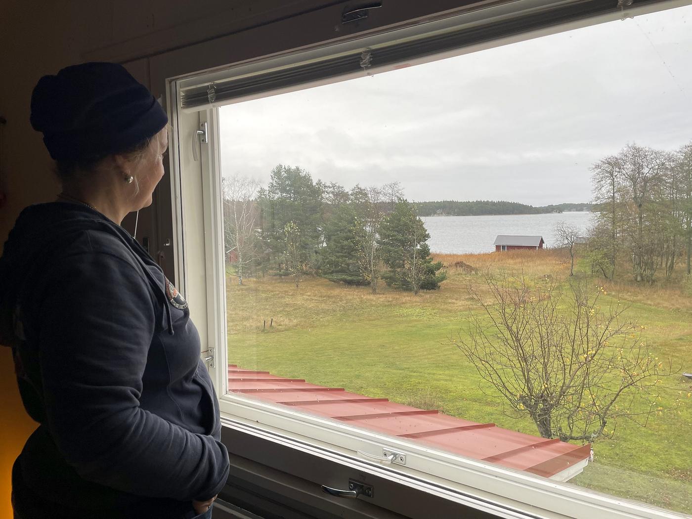 dam tittar ut genom ett fönster mot havet