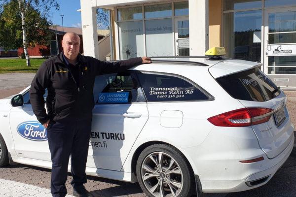 Man står bredvid vit taxibil