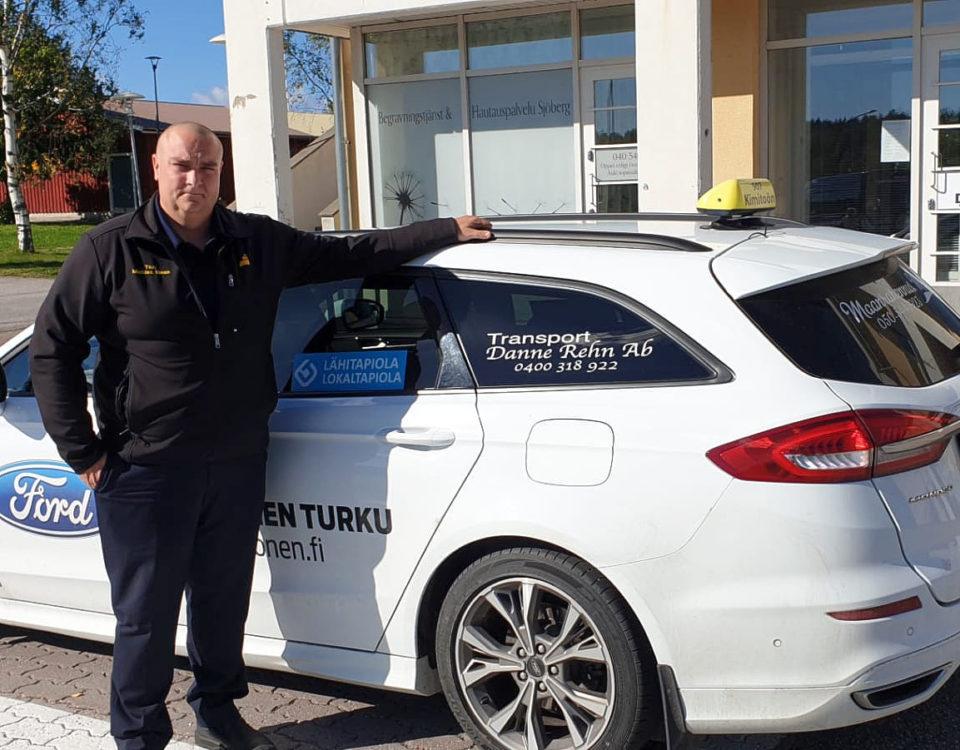Man står bredvid vit taxibil