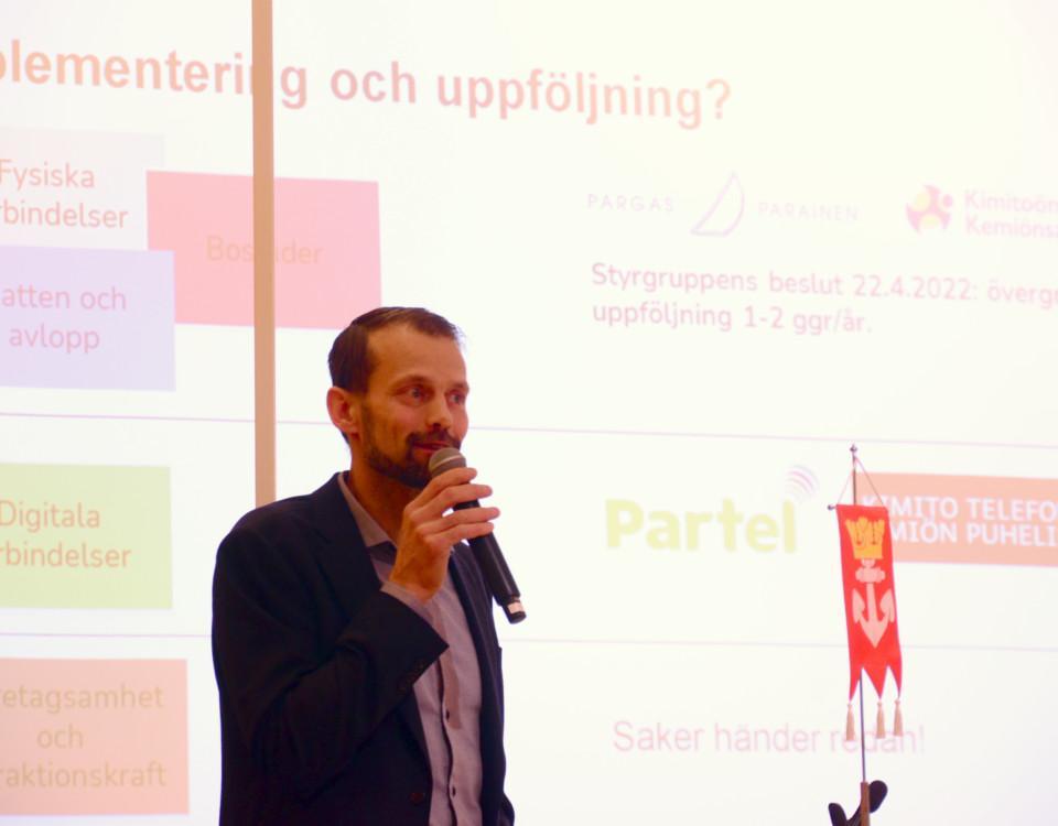 en man med en mikrofon framför en skärm
