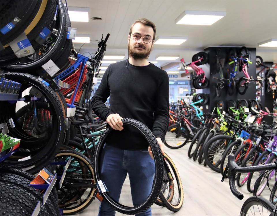 En man håller upp en cykelring i en affär.