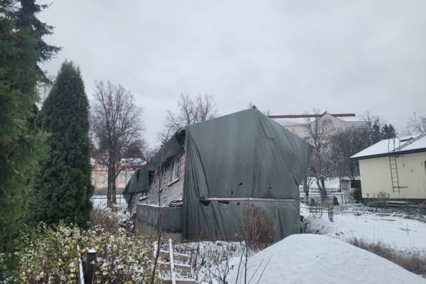 Ett snett trähus vars grund gett efter. Snö på marken.