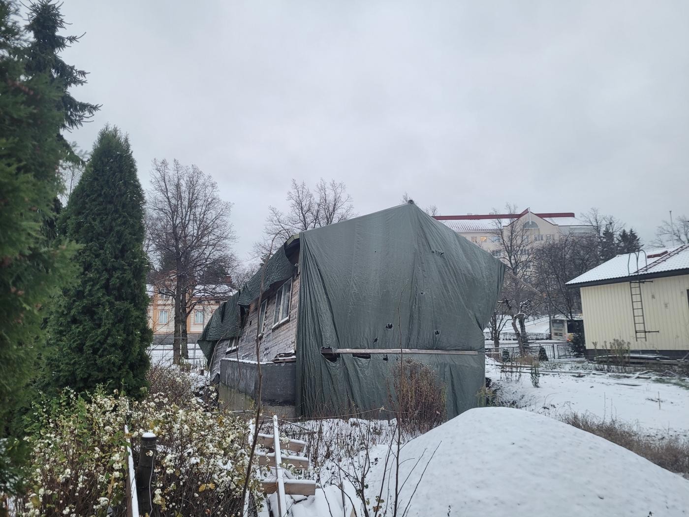 Ett snett trähus vars grund gett efter. Snö på marken.