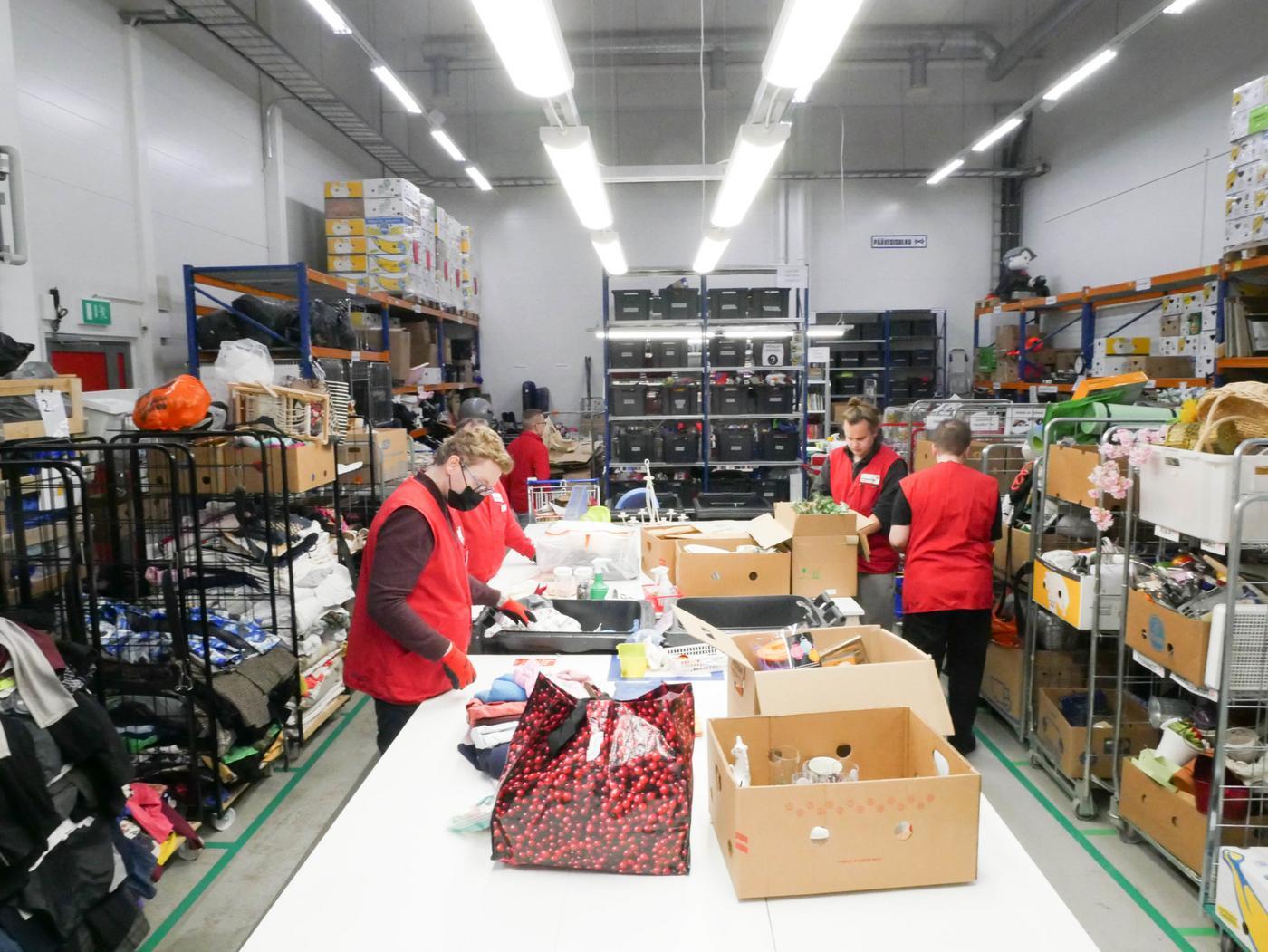 några personer sorterar kläder i ett lager