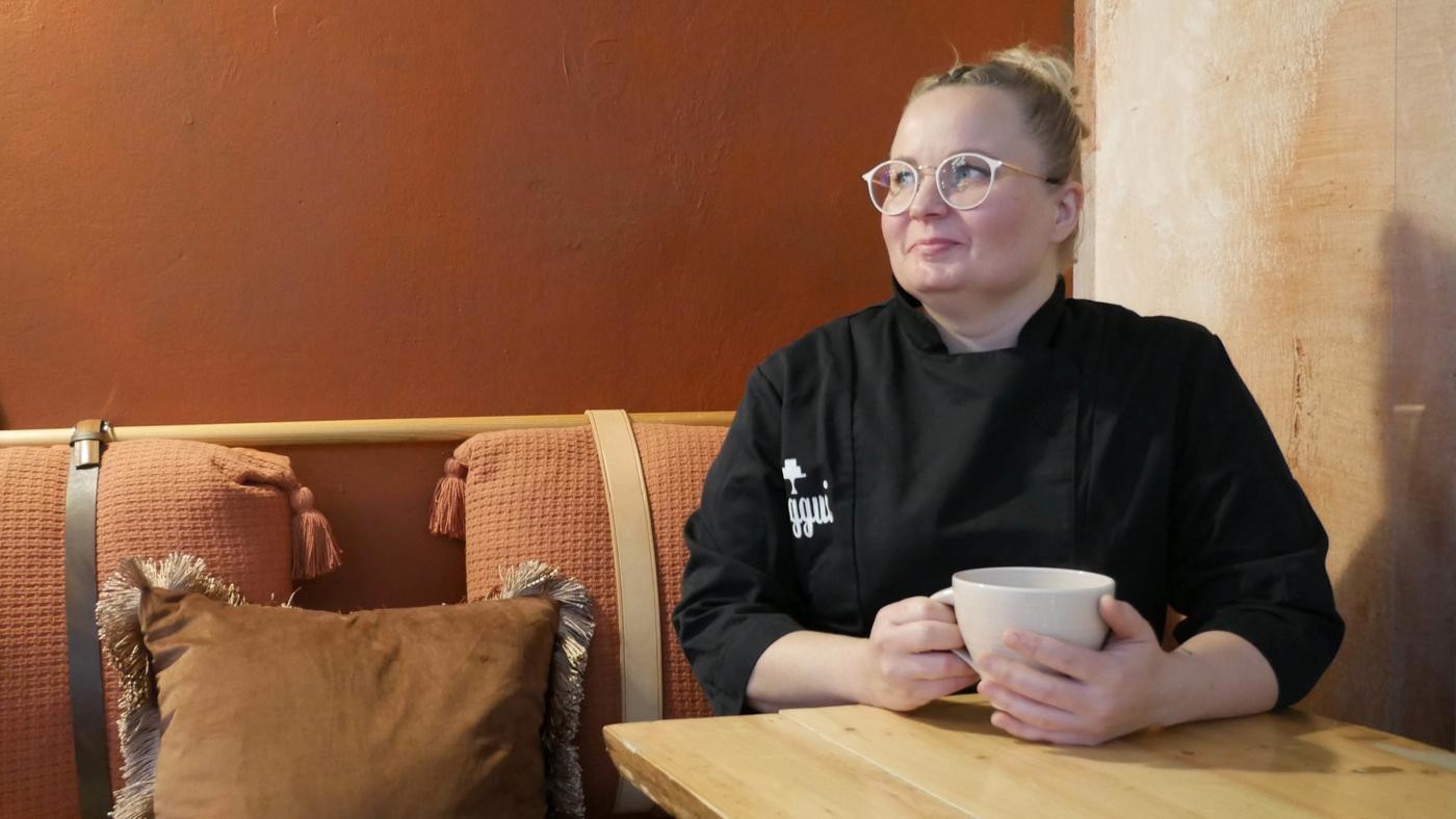 En kvinna sitter vid ett bord och dricker kaffe