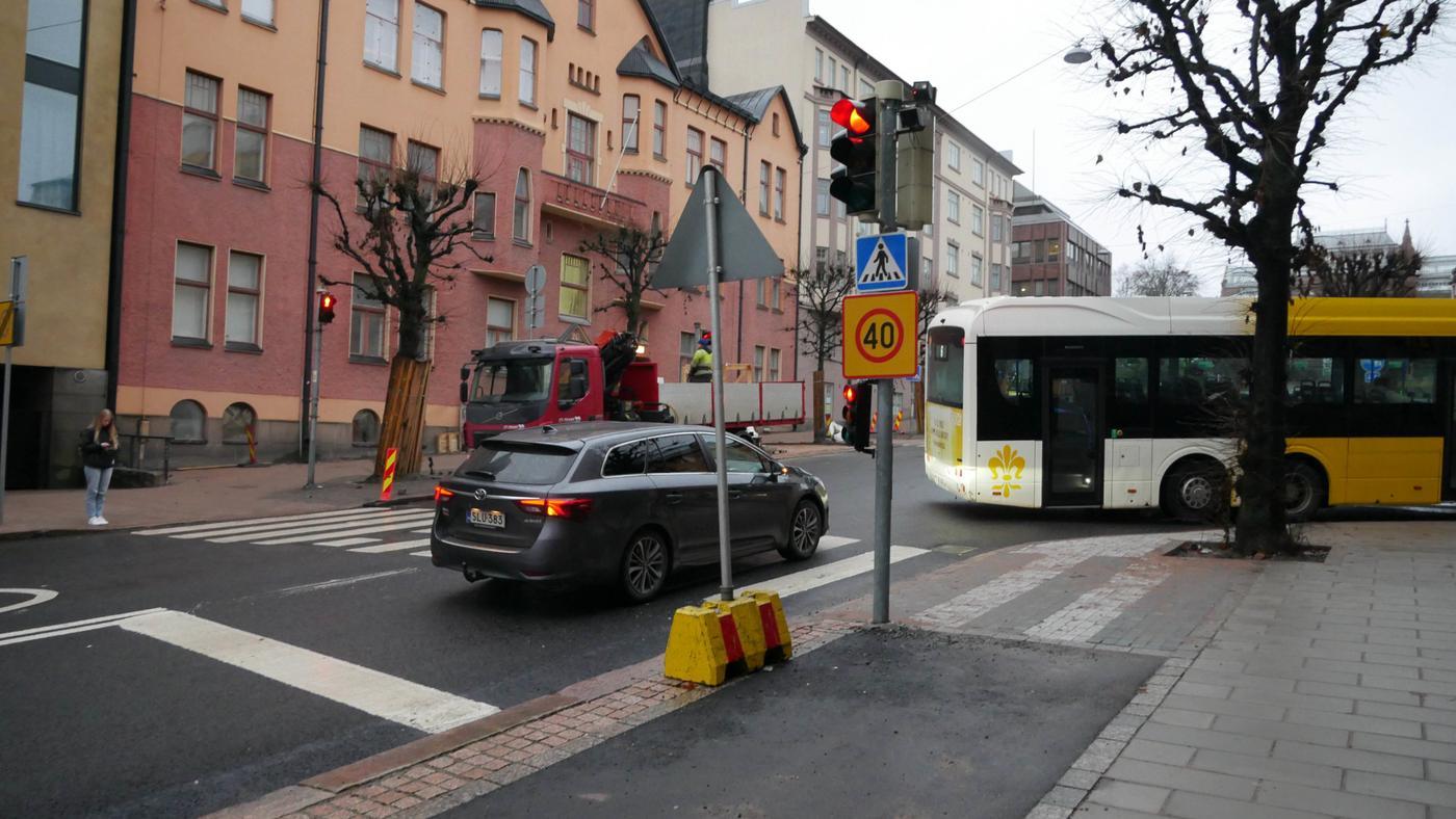 en bil och en buss som kör mot rött ljus