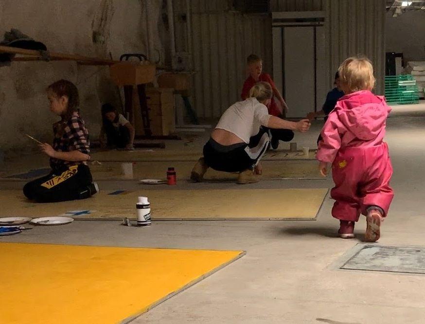 barn och unga målar på ett golv