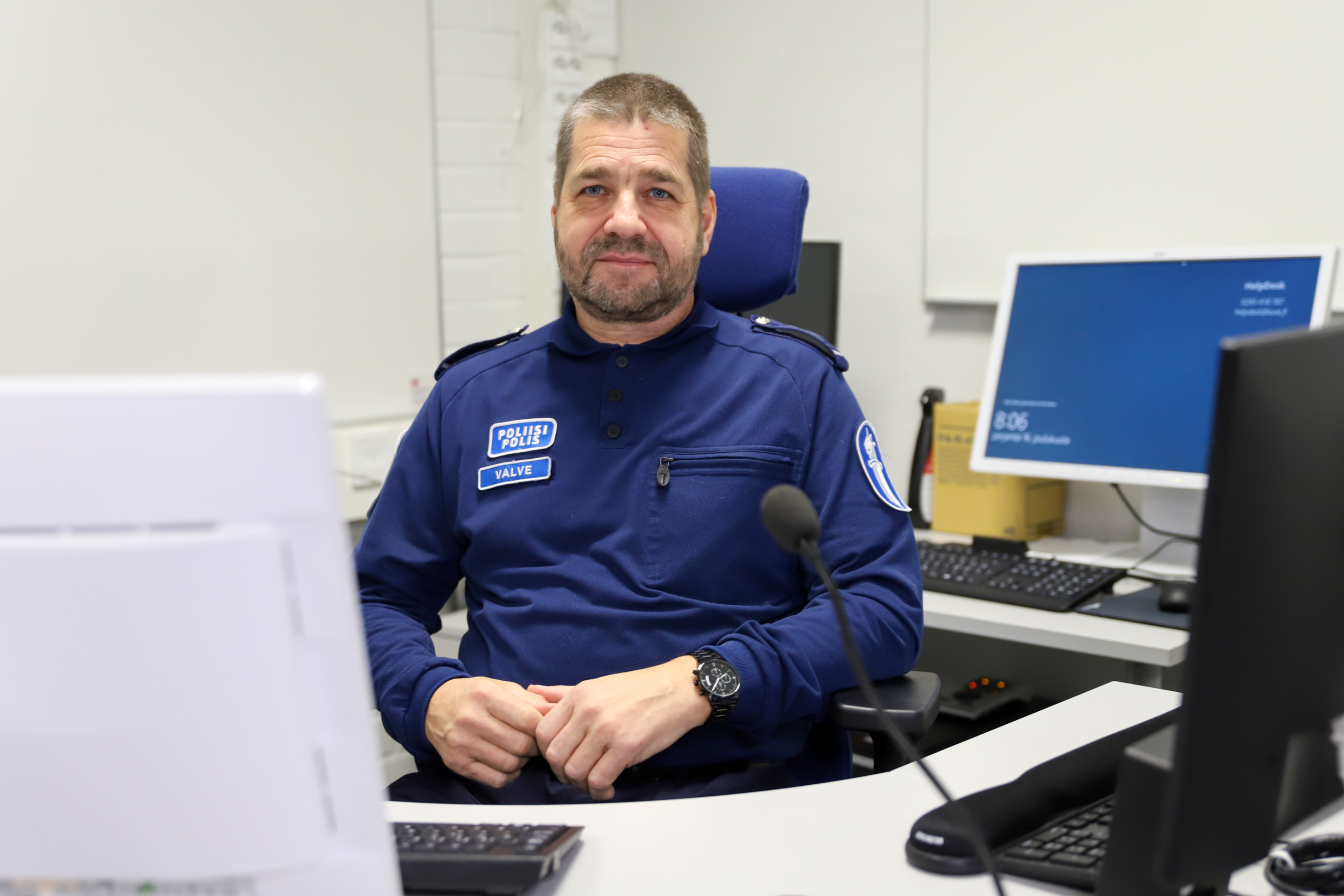 Polis sitter vid arbetsbord med datorer.