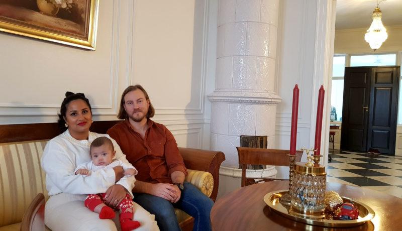 Ett par med en baby i en soffa i ett gammalt hus.