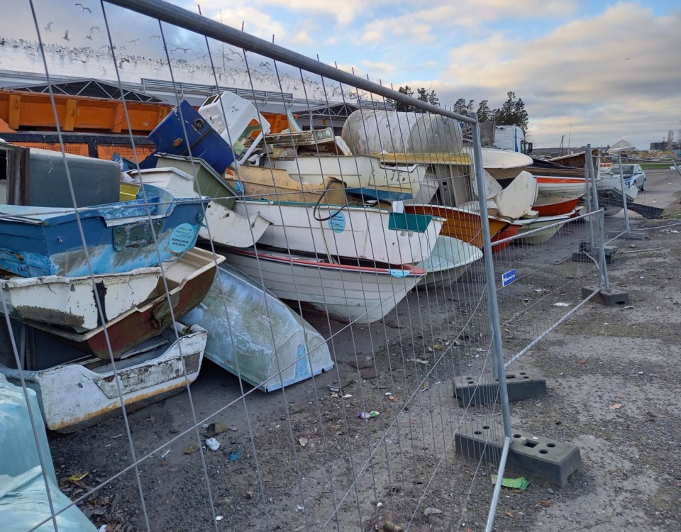 Mindre glasfiberbåtar samlade på hög