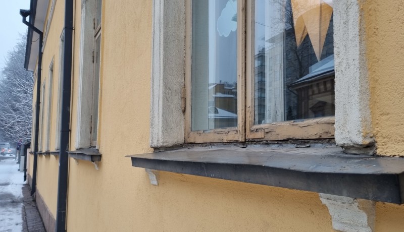 närbild av murken fönsterkarm i gammalt gult hus