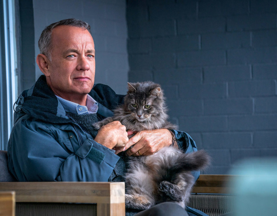 Medelålders man sitter med en grå katt i famnen