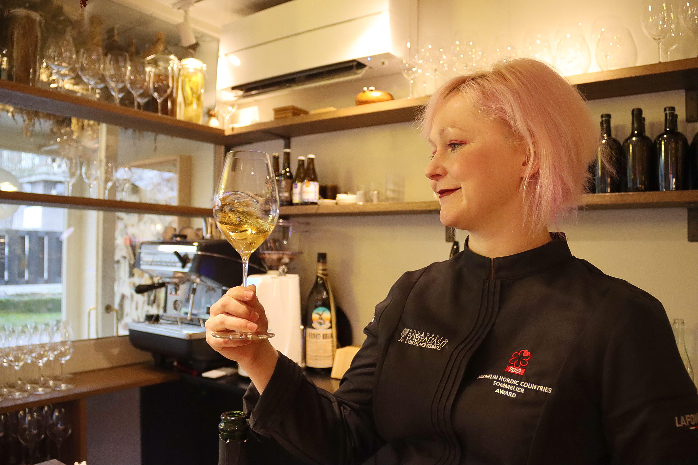 En kvinna som håller upp ett vinglas med vin.