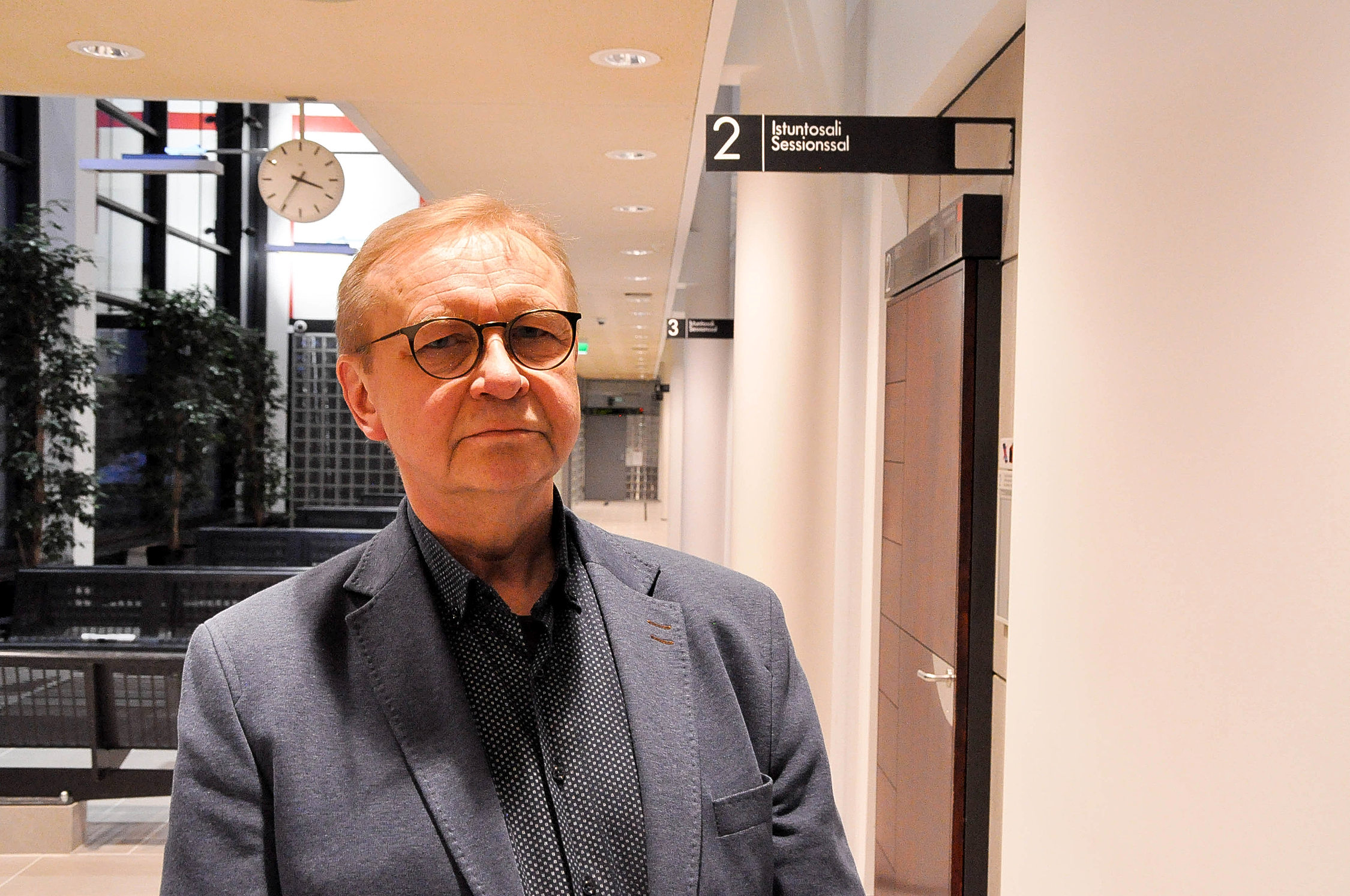 em man med glasögon i en korridor