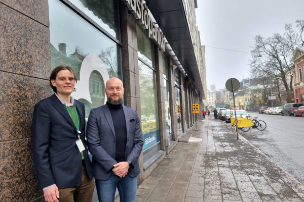 Två män utanför en byggnads skyltfönster.