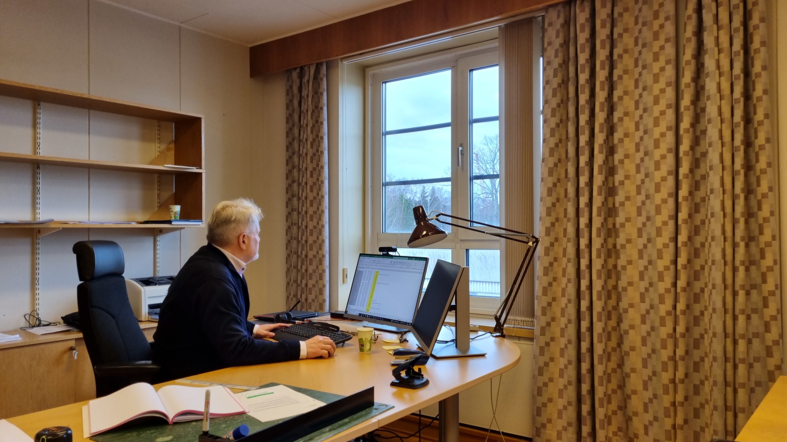 Man sitter framför dator vid skrivbord.