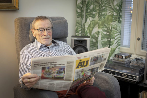 Man sitter i fåtölj och läser ÅU.