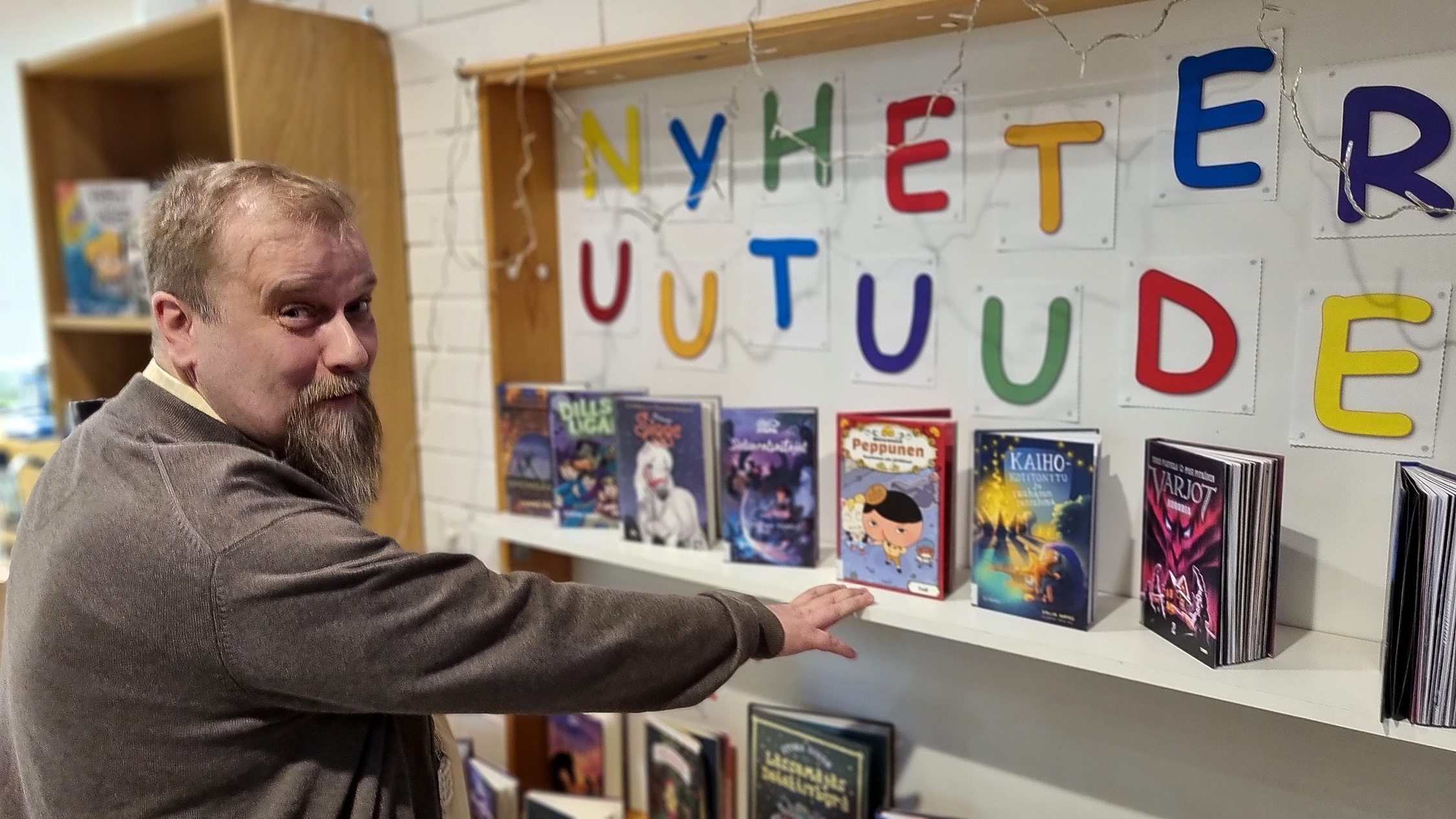 Man pekar på bok i hylla.