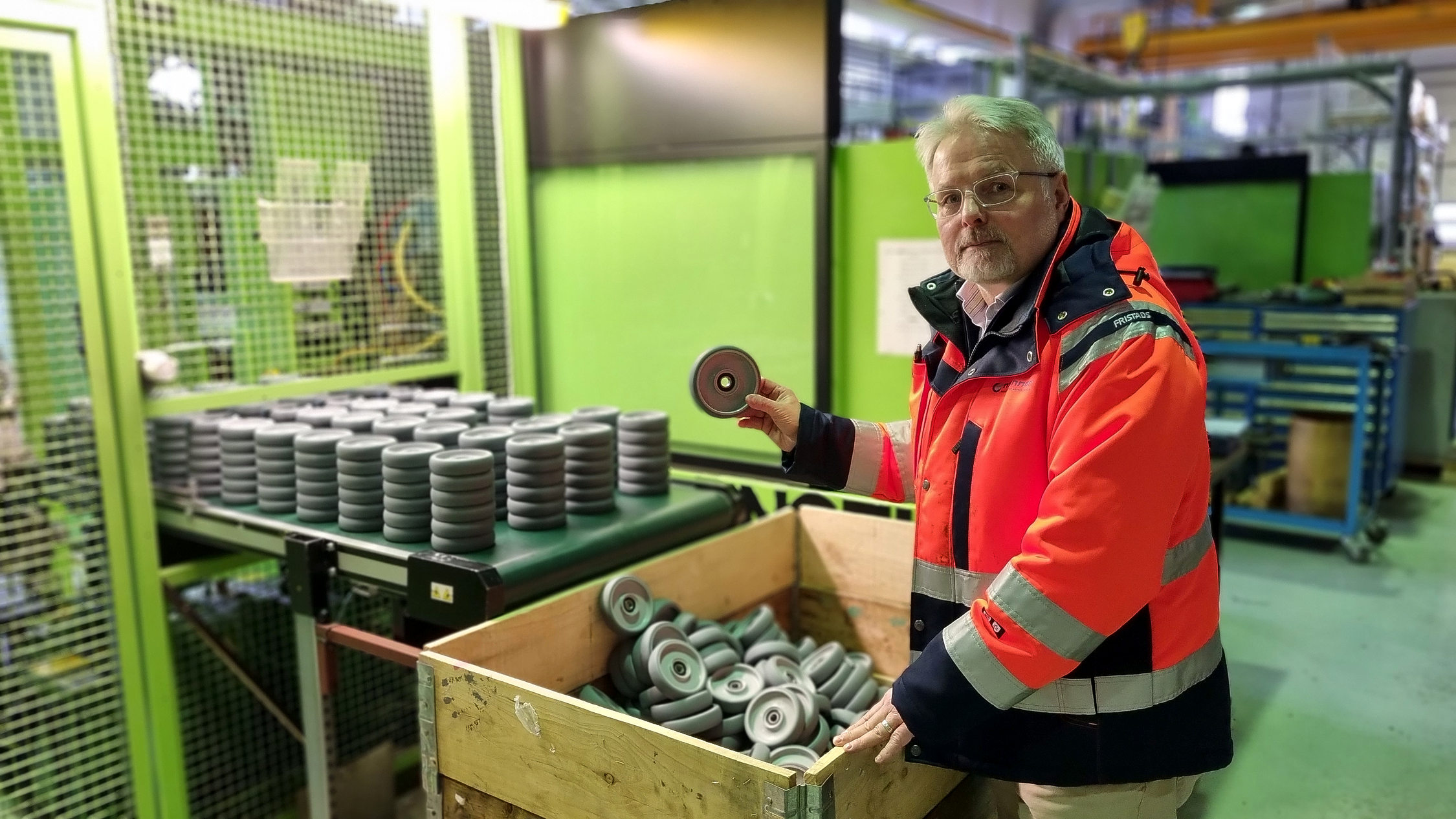 Man håller upp plasthjul i fabrik.