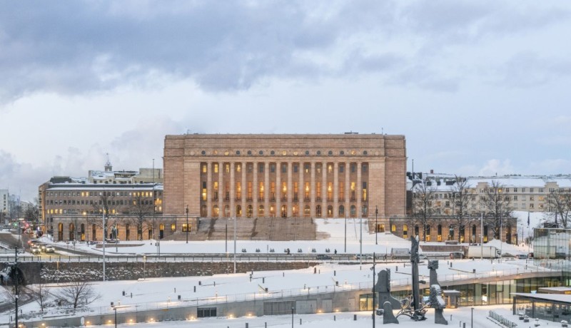 fyrkantigt stort granithus med pelare och snö. Finlands riksdagshus