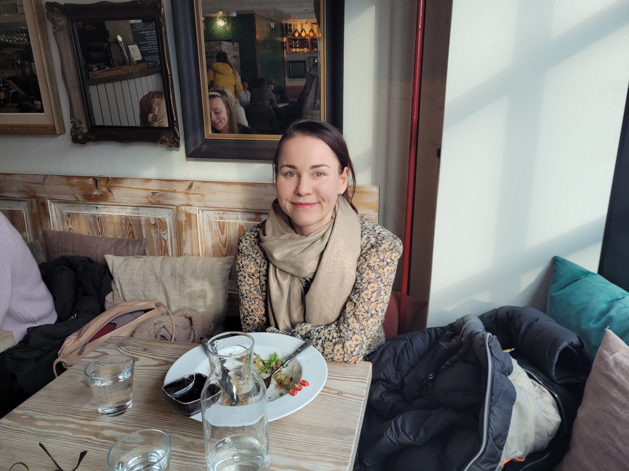 En kvinna sitter med en nästan tom tallrik framför sig i en restaurang.