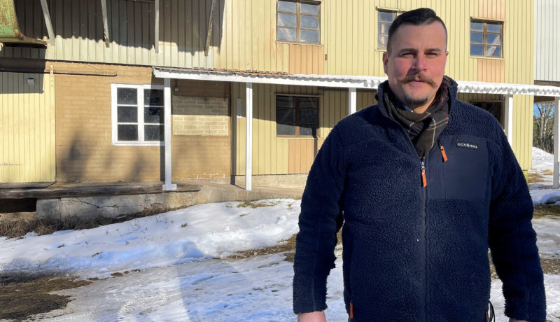 man utanför stor gul byggnad