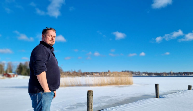 Man på brygga med vinter och stadssiluett i bakgrunden.