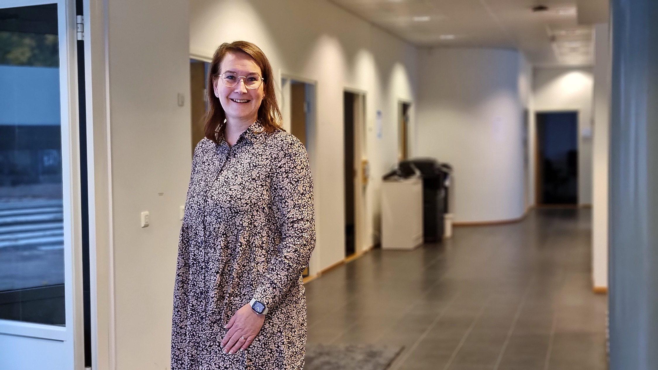 kvinna med glasögon står i korridor