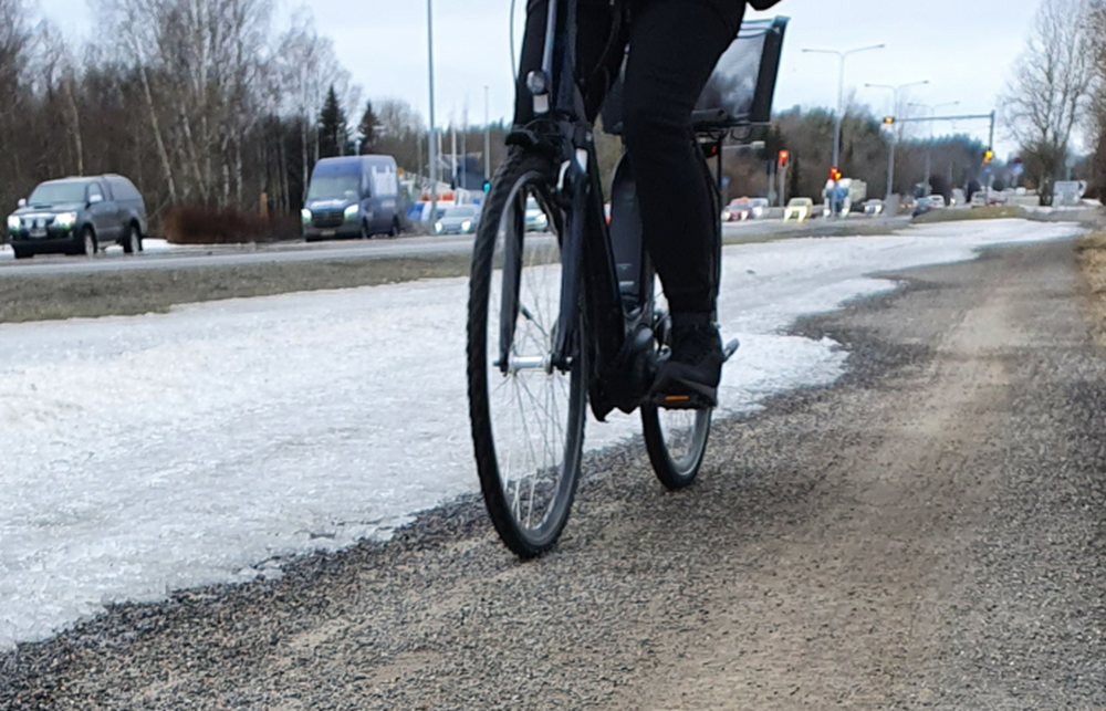 En person som cyklar på en cykelväg med grus.