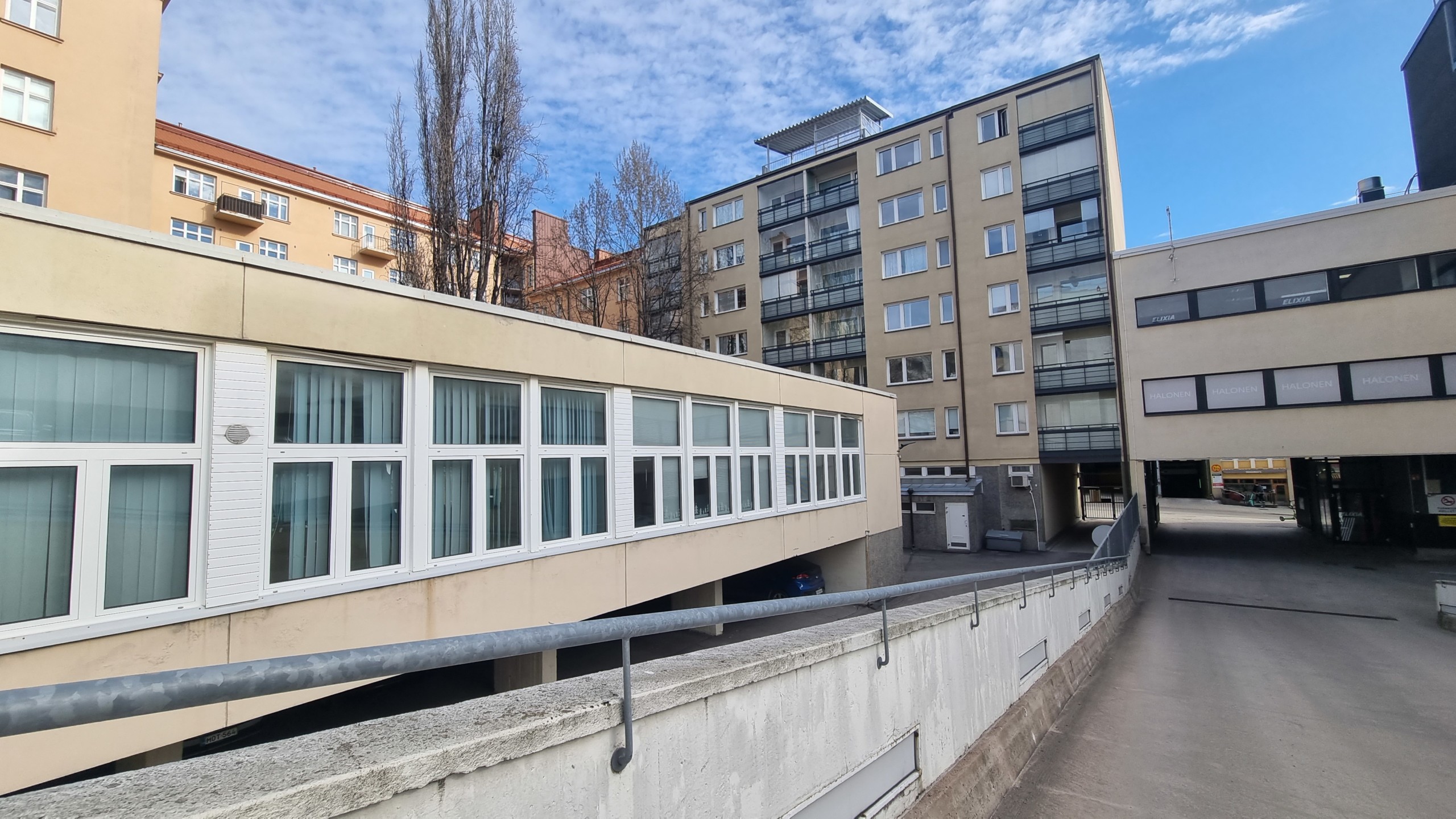 låg byggnad inne på höghusgård, höghus i bakgrunden
