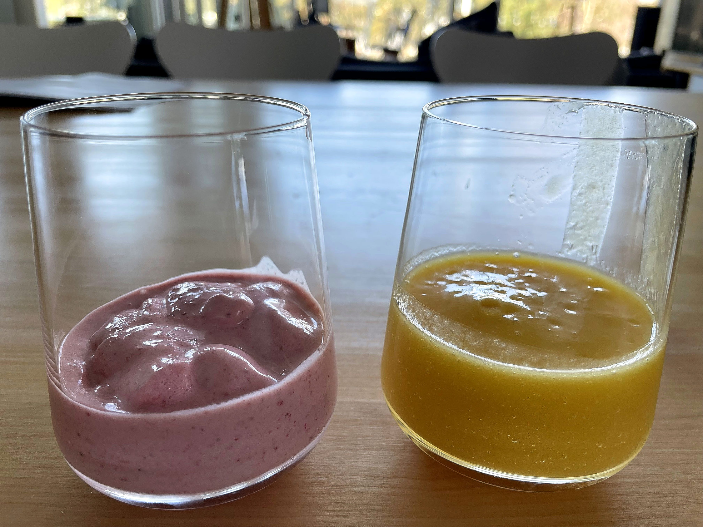 Två halvfulla glas med rosa och gul smoothie.