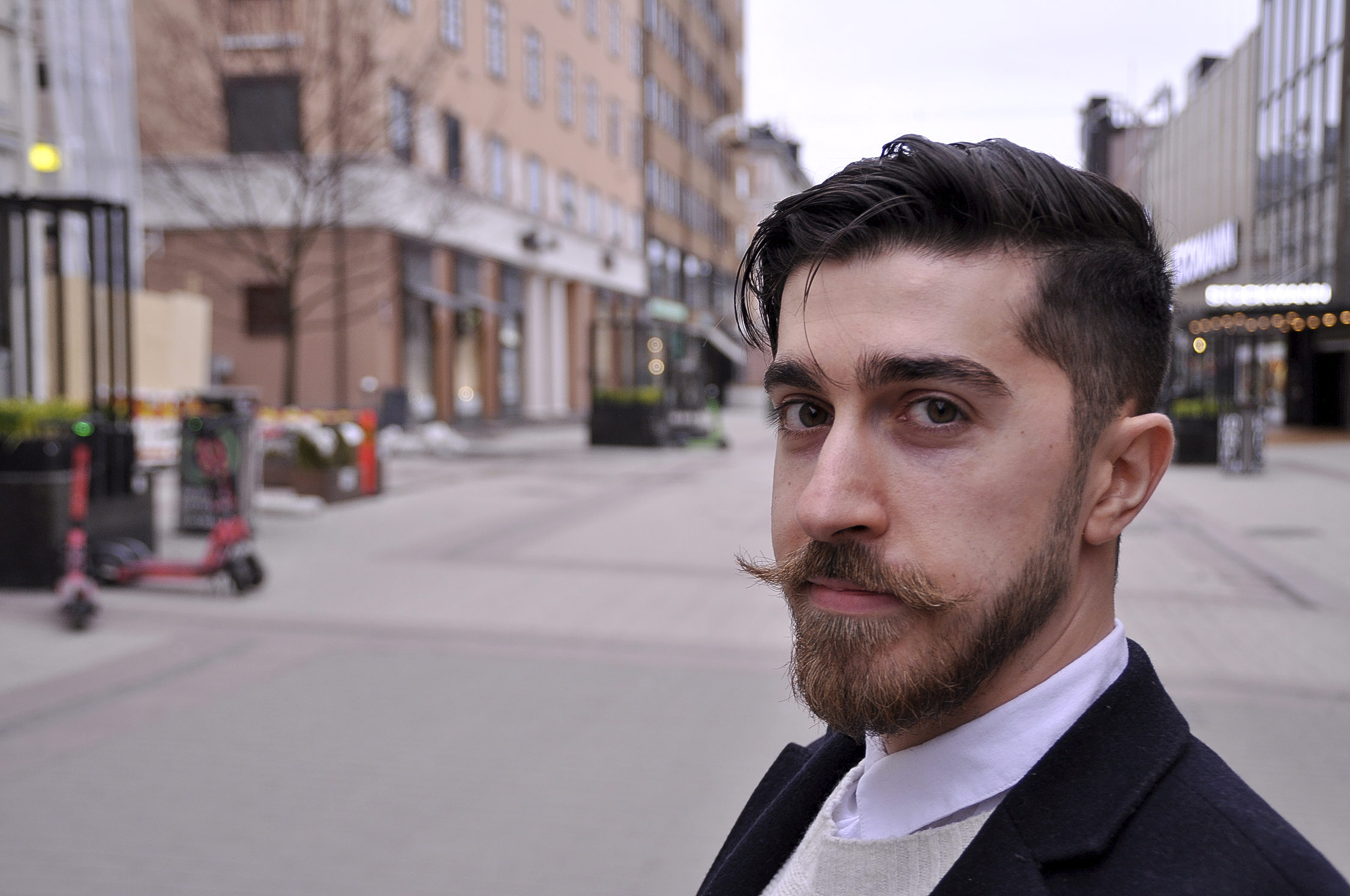 en man står på en gågata och tittar i kameran