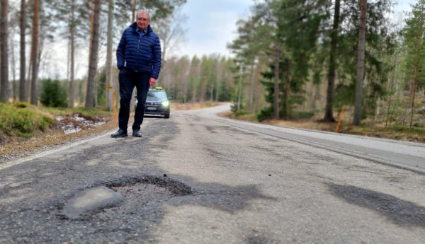 Gropig väg med man och bil i bakgrunden.