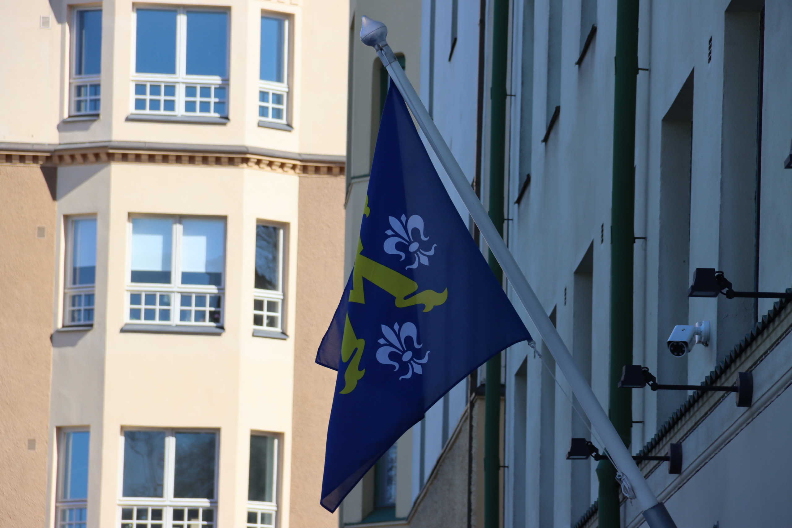 En flagga med ett gammalt hus i bakgrunden.