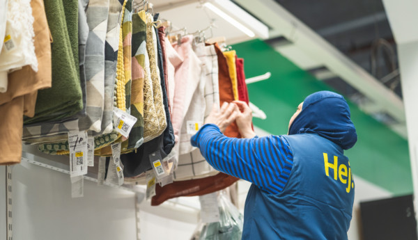 En person som sorterar textilier som hänger på rad.