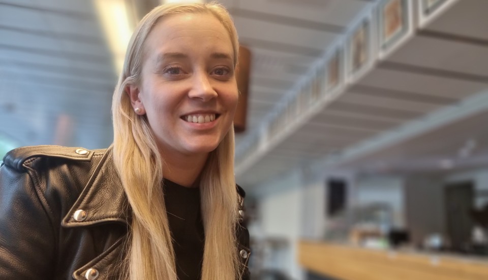 Ung kvinna klädd i svart läderjacka som ler