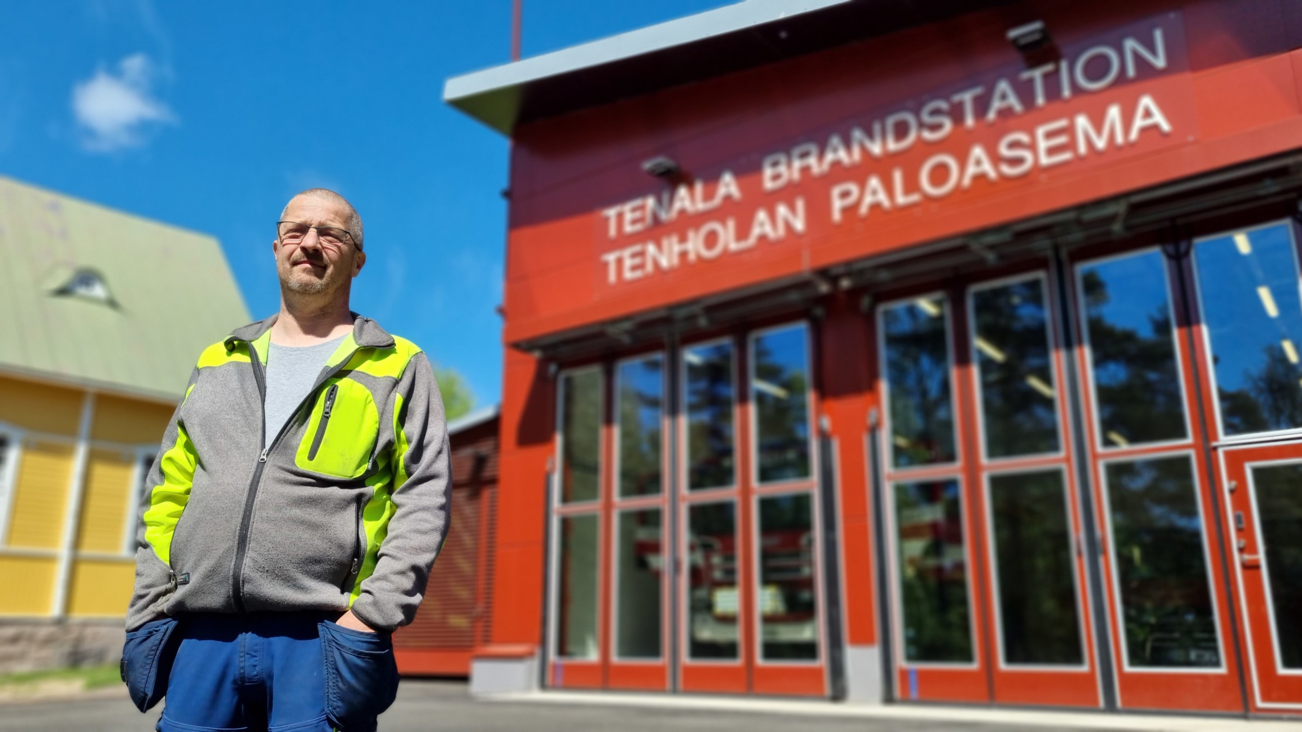 Man framför röd brandstation.