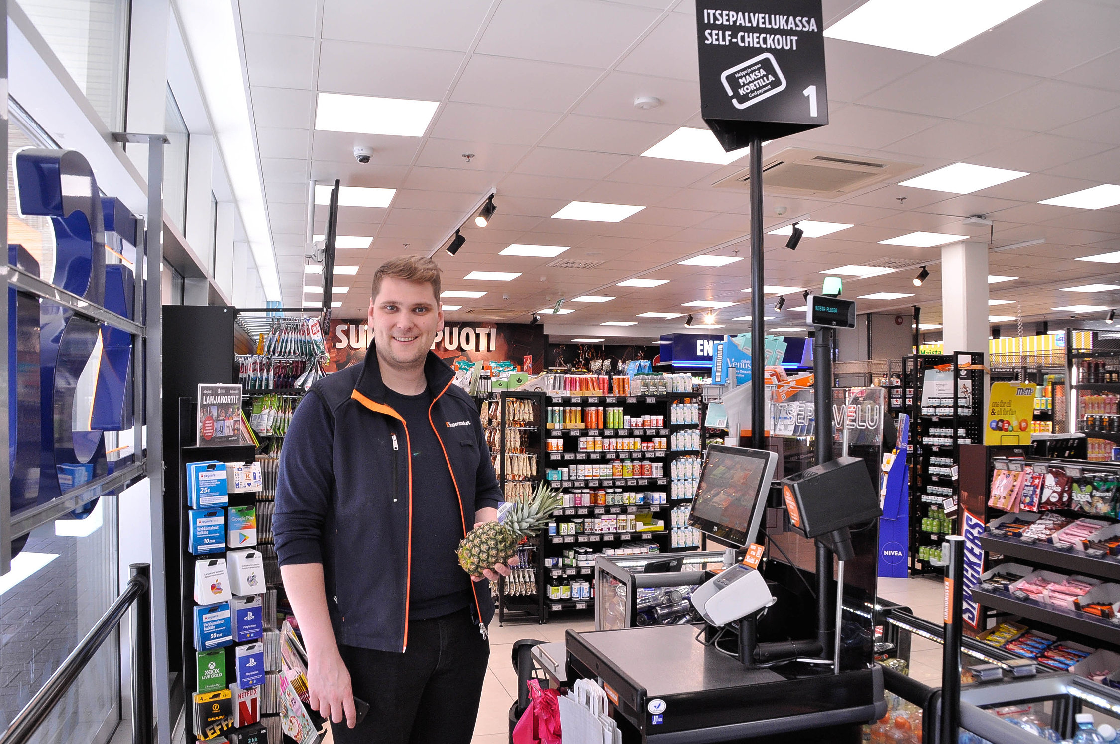 en köpman står vid snabbkassorna i en butik