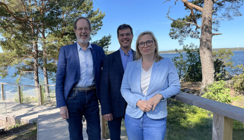 tre personer på en trätrappa vid havet