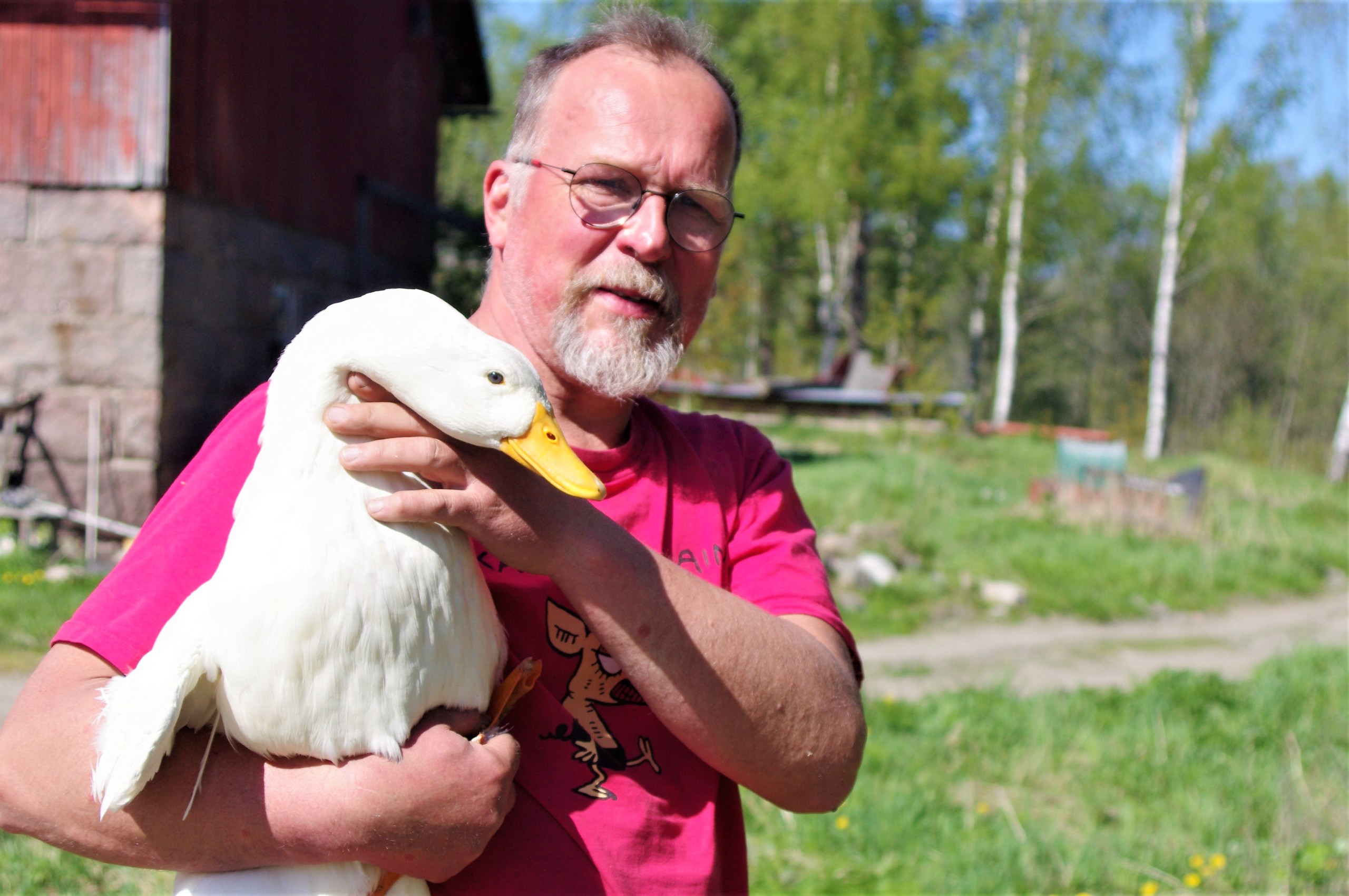 En man med en vit anka i famnen