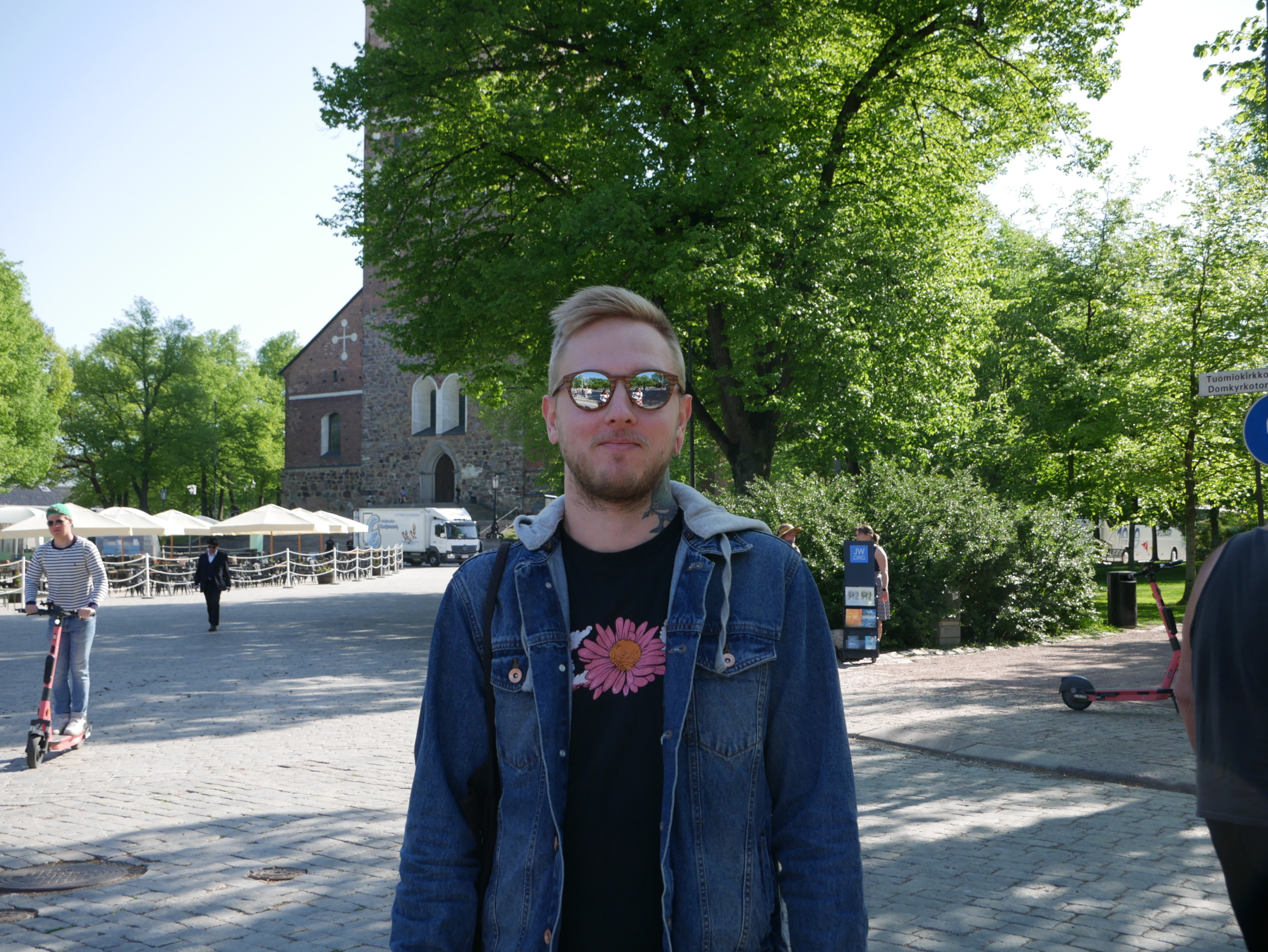 Ung man med solglasögon i somrig stadsmiljö